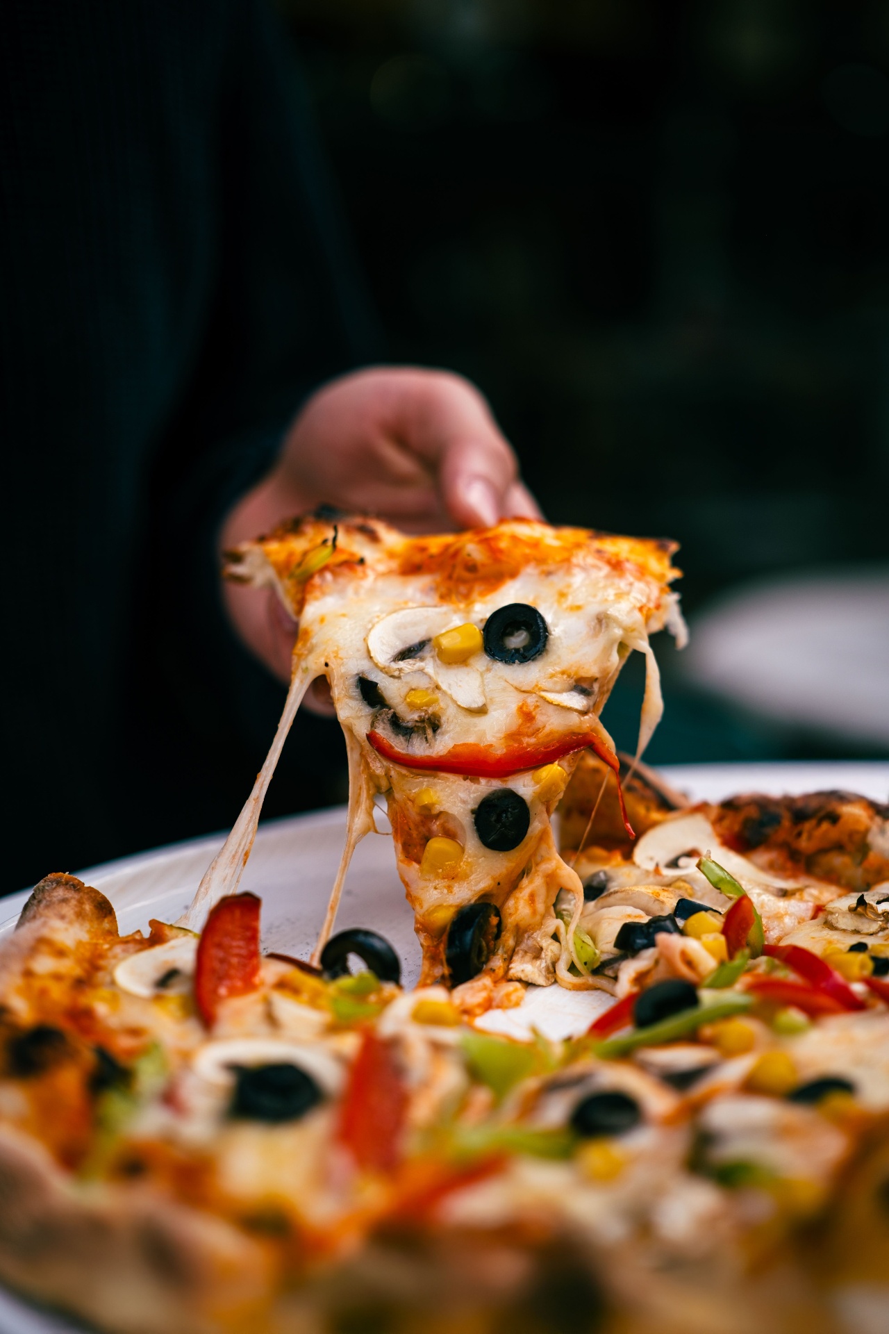Cheese pull from a Villa Pizza slice loaded with toppings